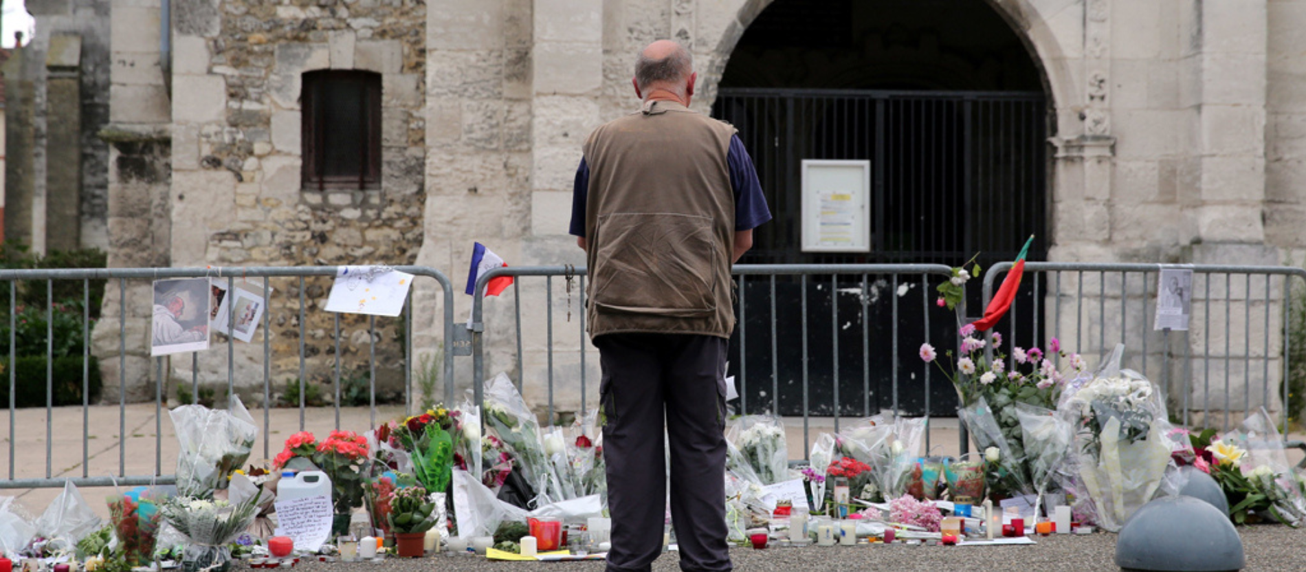 Ein Mann steht vor einem Blumenmeer zum Gedenken an Jacques Hamel in Rouen