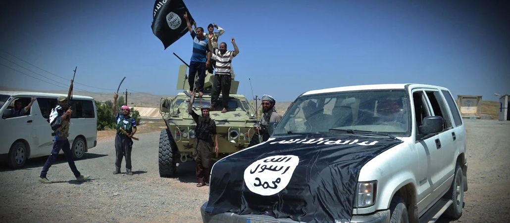 Ein Auto und jubelnde Männer mit der Flagge des Islamischen Staats.