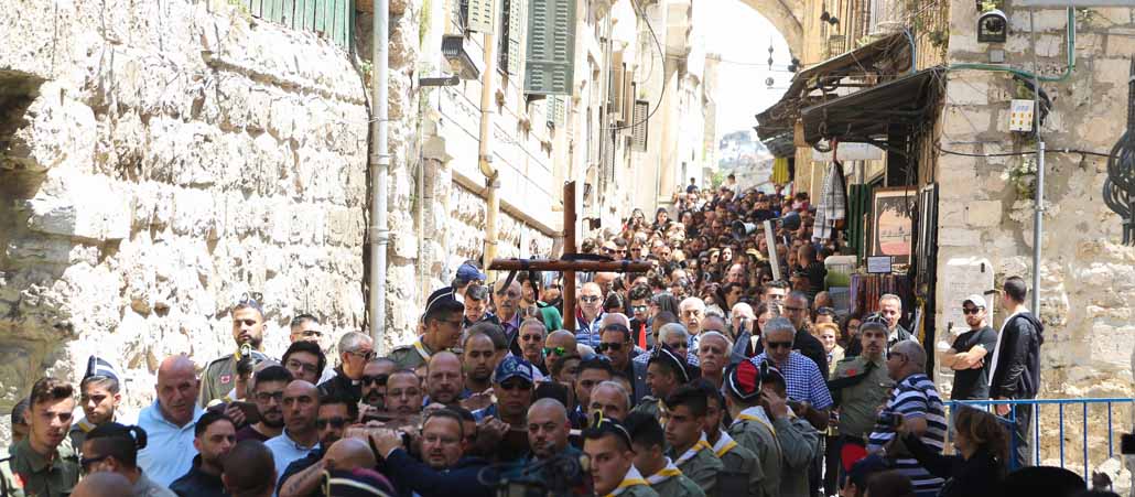 Menschenmanssen mit Kreuzen drängen sich durch eine enge Gasse
