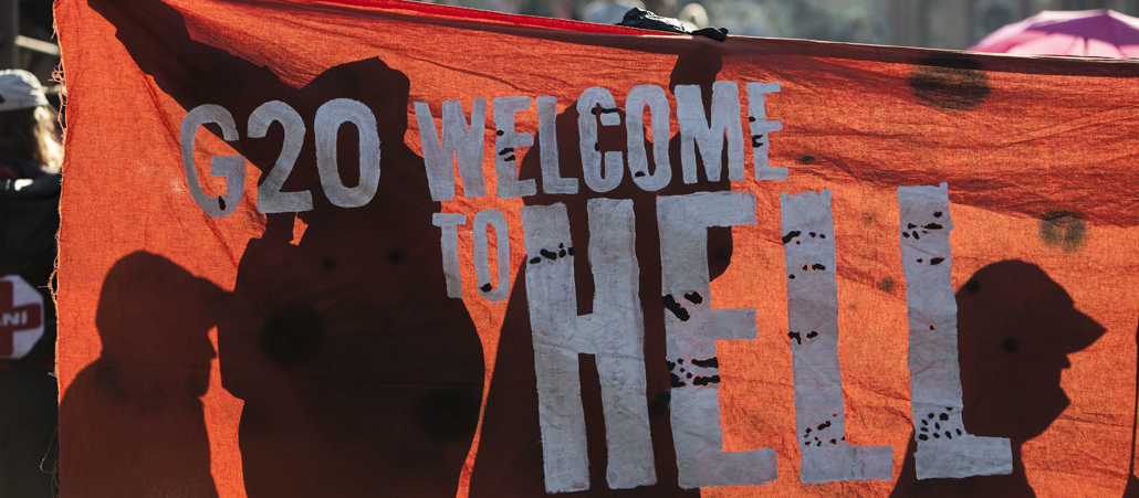 G20-Demonstranten halten ein rotes Banner mit der Aufschrift "G20 Welcome to Hell".