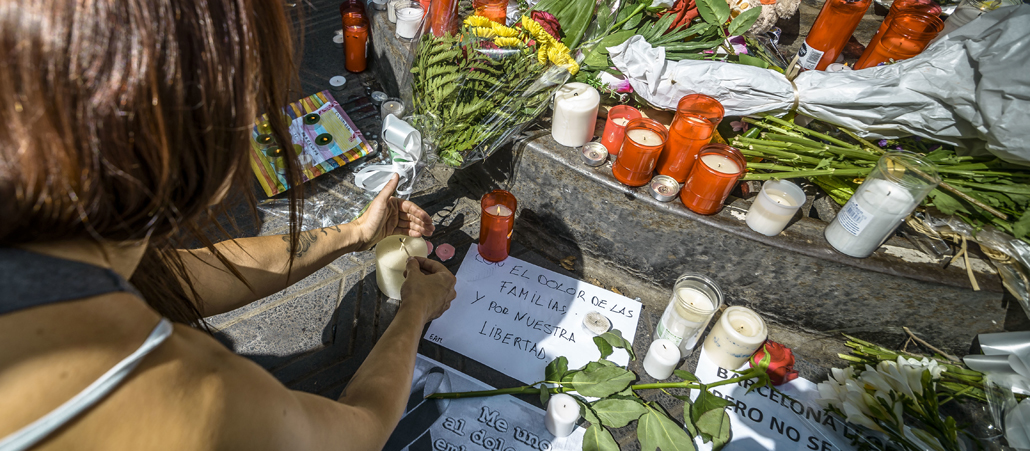 A mourner places a candle at a makeshift memorial at Canaletas Fountains in Las Ramblas
