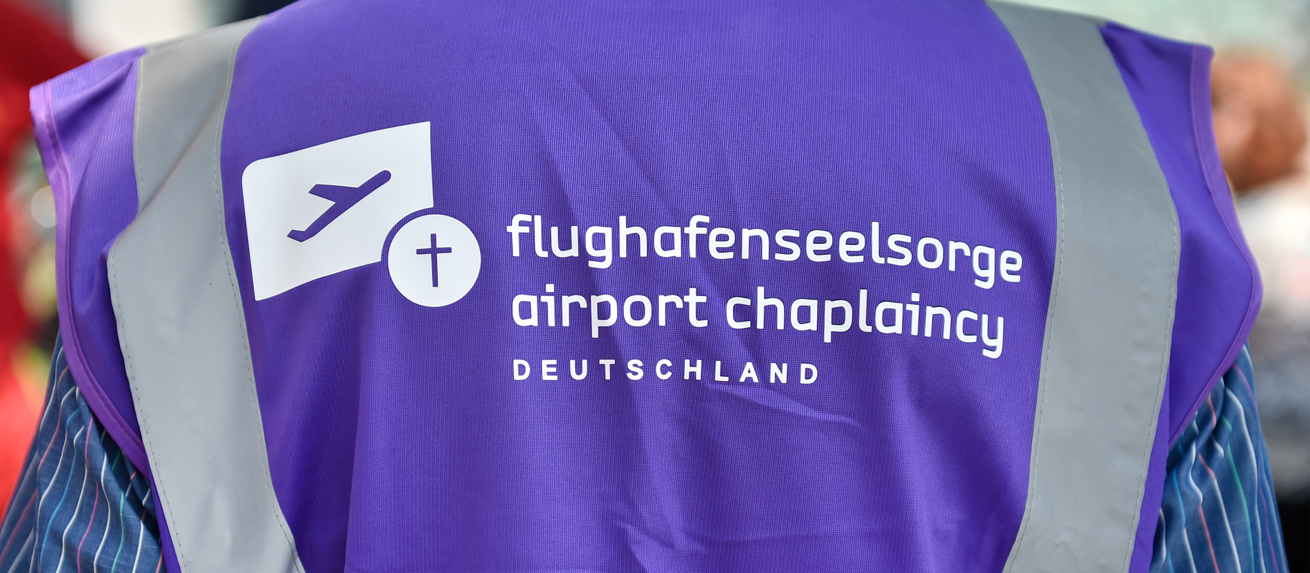 Ein Mann trägt die violette Warnweste der Flughafenseelsorge des Dresdner Flughafens.