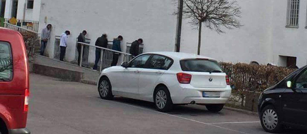 Sechs Menschen lehnen mit dem Kopf an einer Kirchenwand