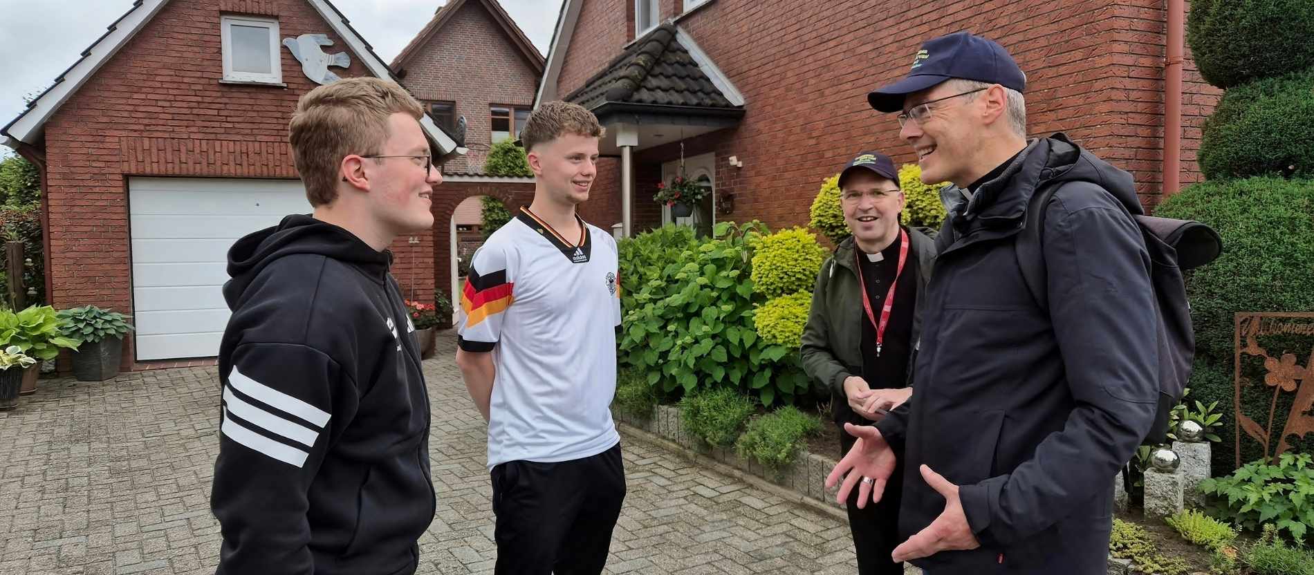 Bischof Heiner Wilmer spricht mit zwei Jugendlichen, die Deutschland-Trikots tragen