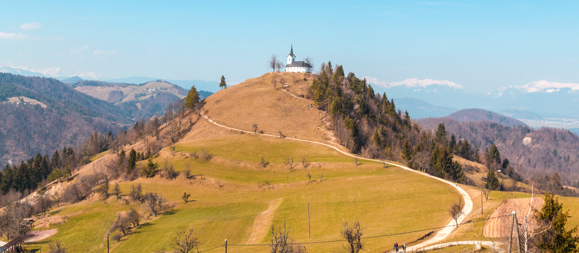Eine geschlungener Weg führt zu einer kleinen Kapelle auf dem Gipfel eines Hügels.
