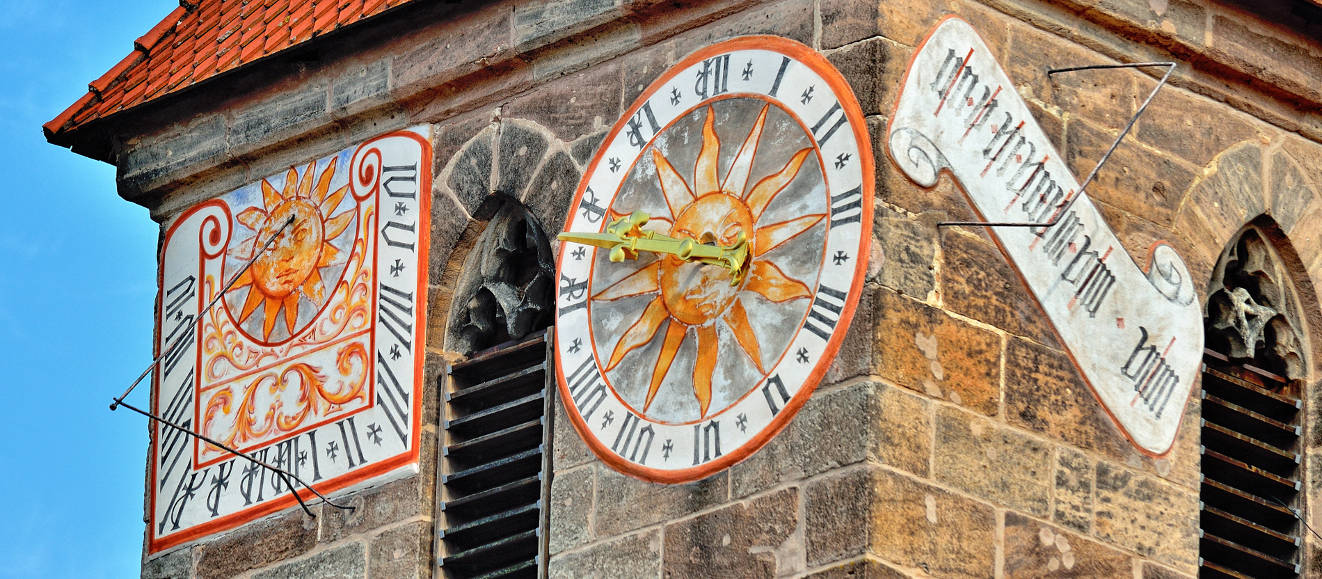 Historische Uhr und Sonnenuhr an einem Kirchturm
