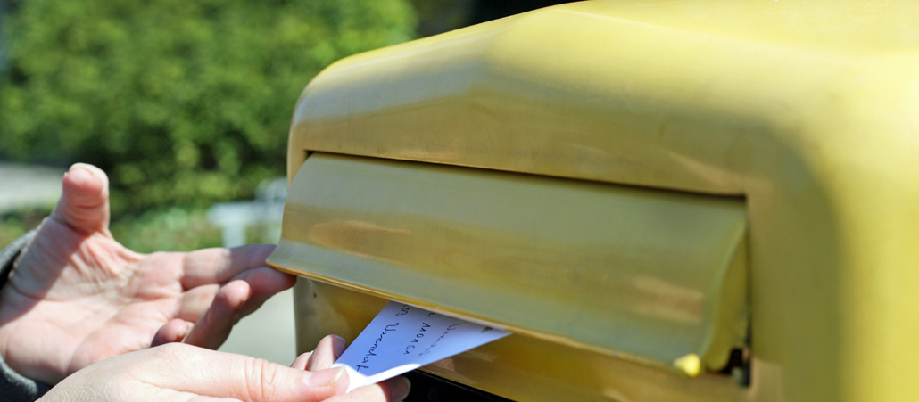 Ein Mensch steckt einen Briefkasten in einen Briefkasten.