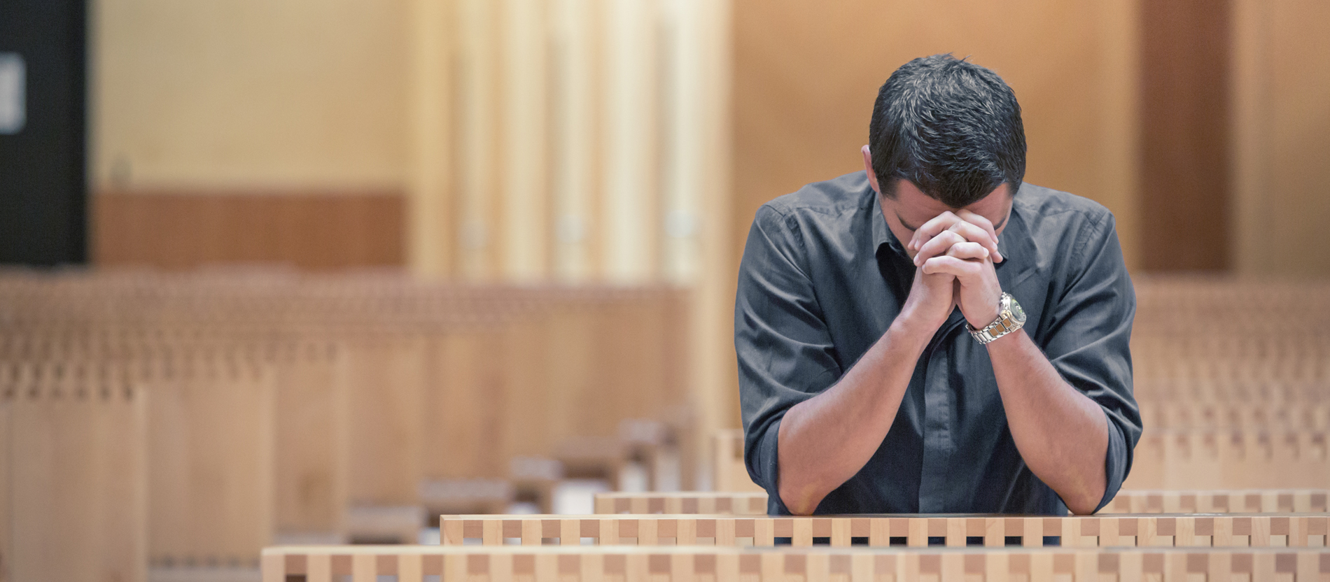 Ein Mann kniet betend in einer Kirche.