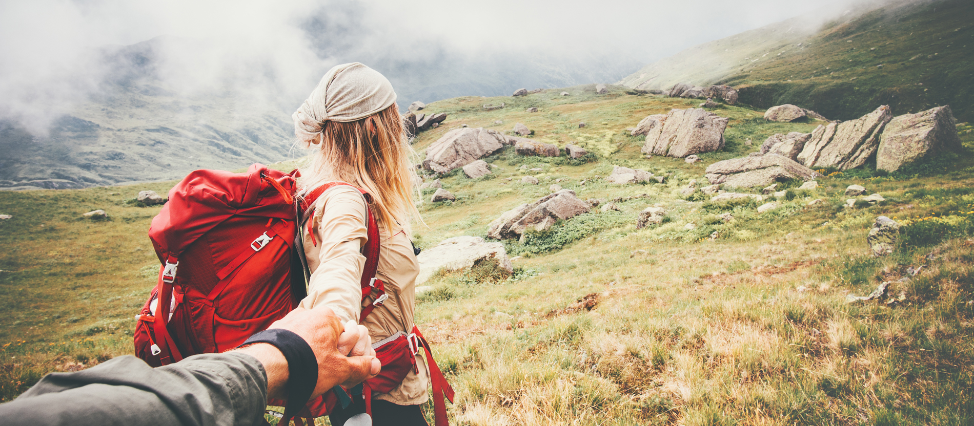 Eine junge Frau wandert mit ihrem Partner durchs Gebirge.