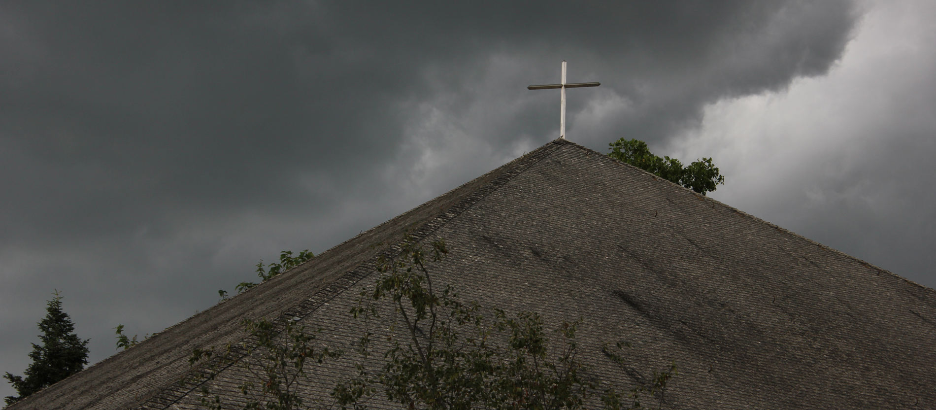 Hinter einer Kirche in Freiburg ziehen dunkle Wolken auf.