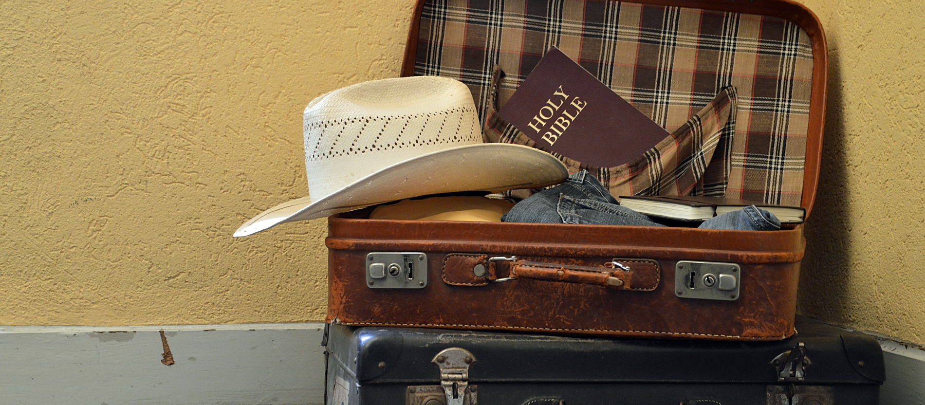 Ein gepackter Koffer mit Hut, Kleidung und einer Bibel.