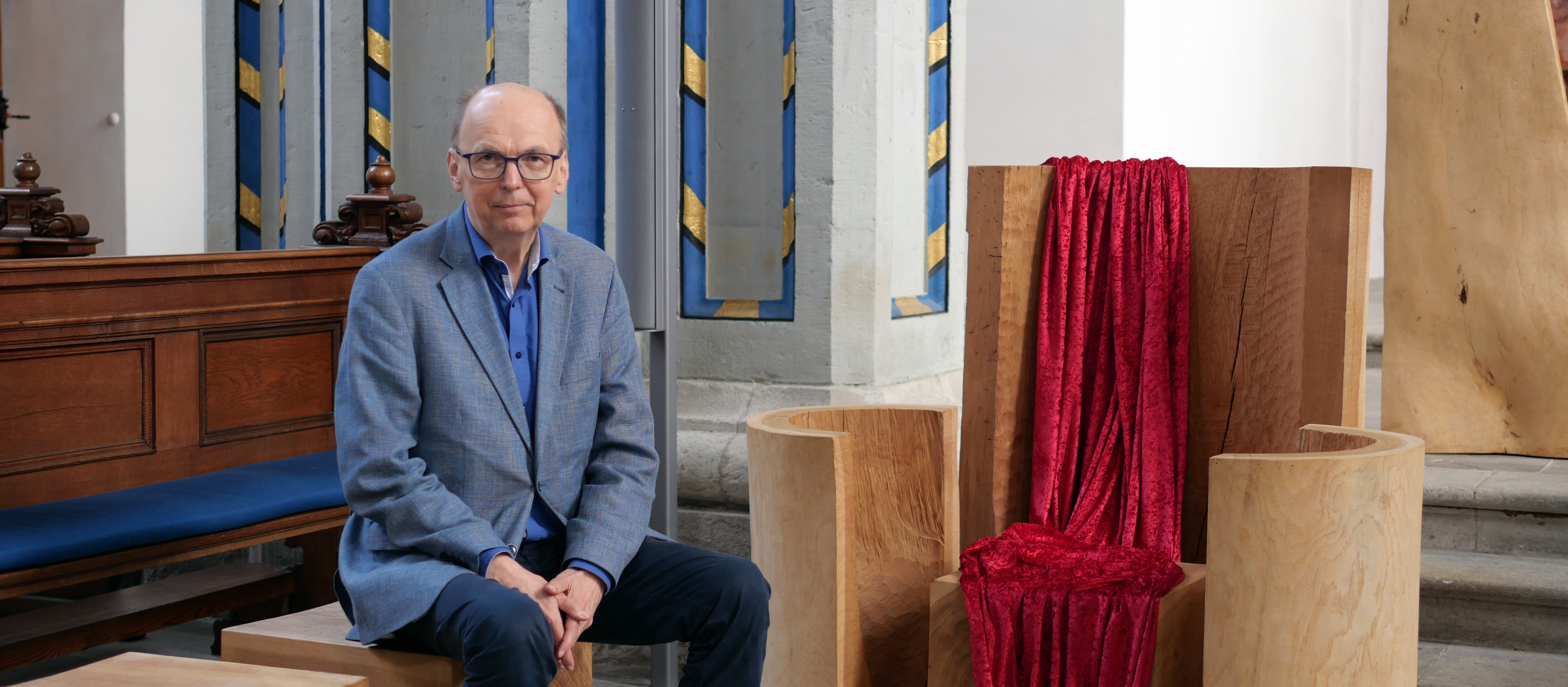 Bischof Matthias Ring sitzt in Zivil neben der leeren Kathedra der Bonner Namen-Jesu-Kirche