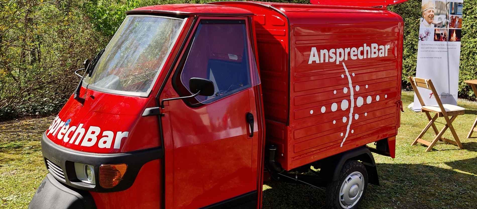 Auf dem Bild sieht man einen roten Kleinbus mit der Aufschrift "AnsprechBar" 