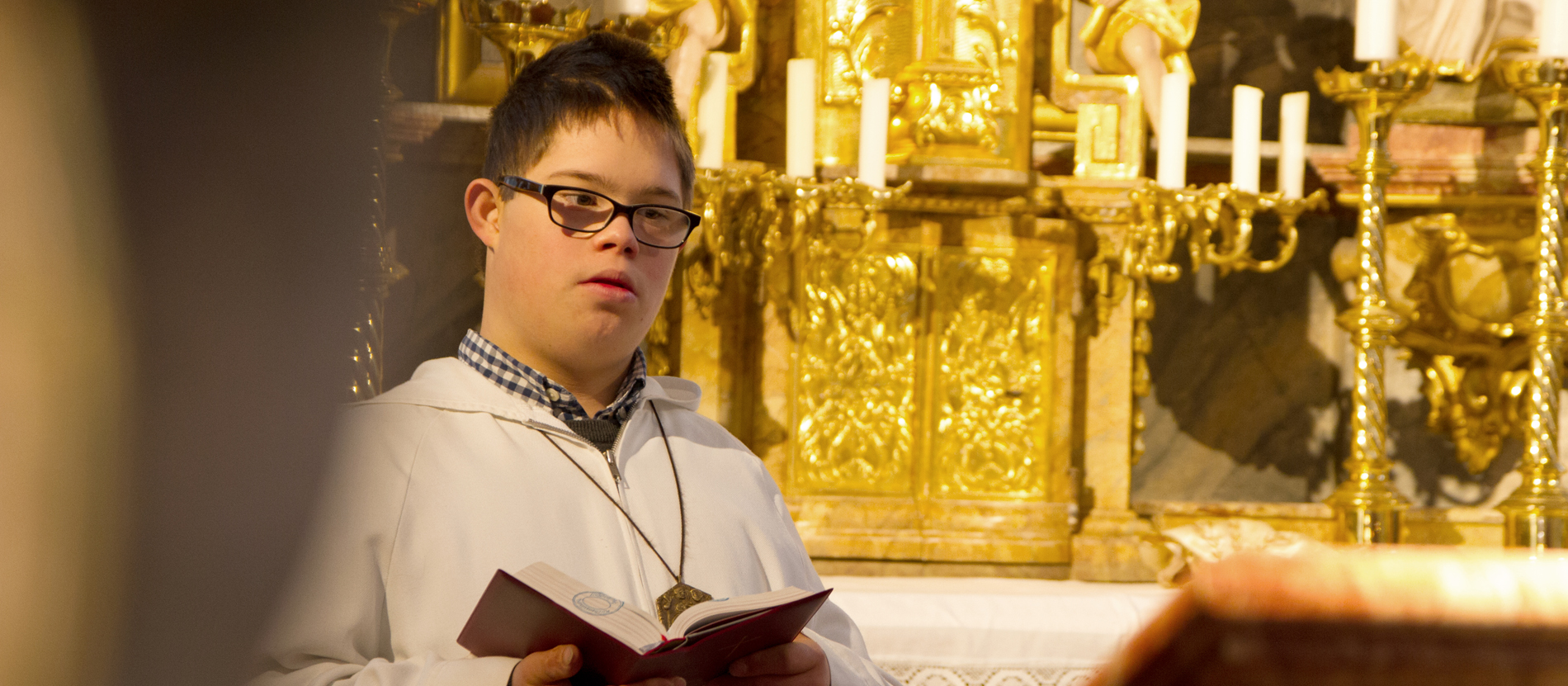 Ein Ministrant hält im Gottesdienst ein Gesangbuch.