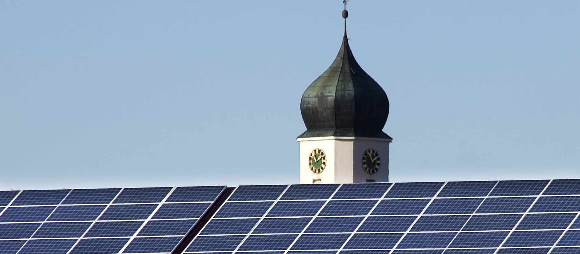 Eine Photovoltaik-Anlage steht vor eine Kirche.