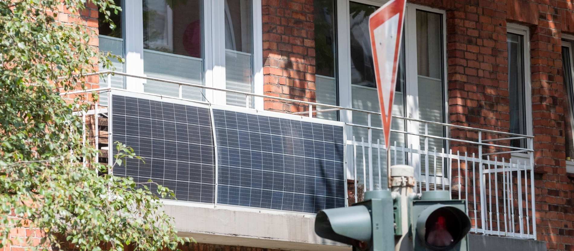zwei Solarpanelen hängen an einem Balkon eines Wohnhauses. 