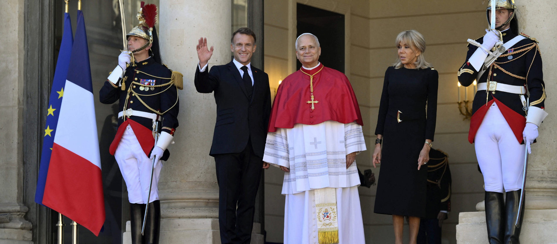 Papst Leo steht zwischen dem französischen Präsidenten Macron und seiner Frau Brigitte an der Treppe des Elysée-Palasts