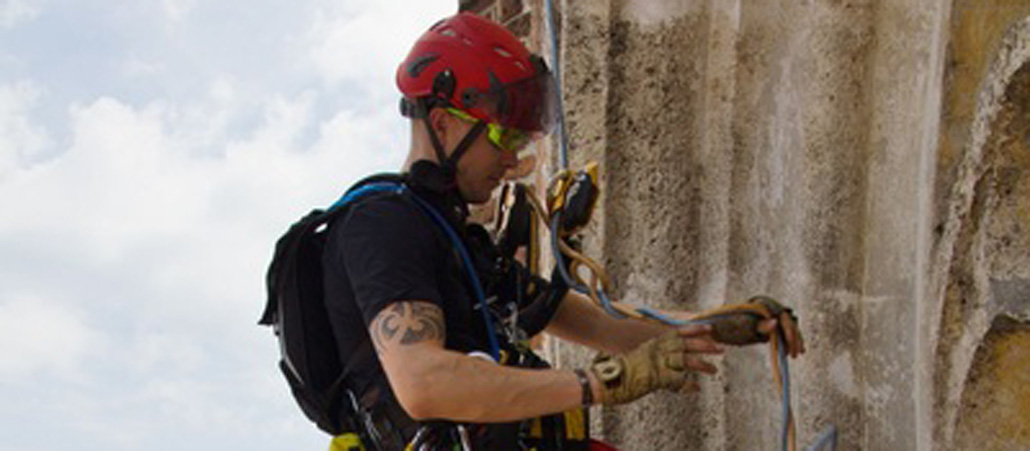 Ein Mann klettert an einem Kirchturm entlang