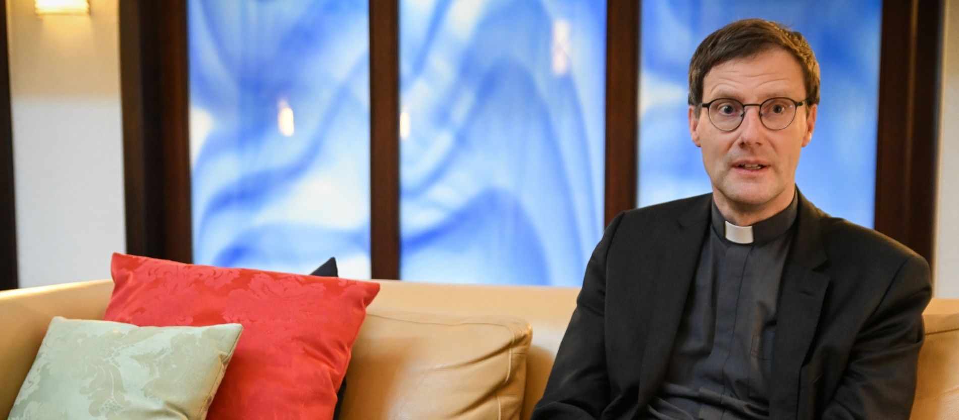 Weihbischof Martin Marahrens sitzt auf einem Sofa und spricht