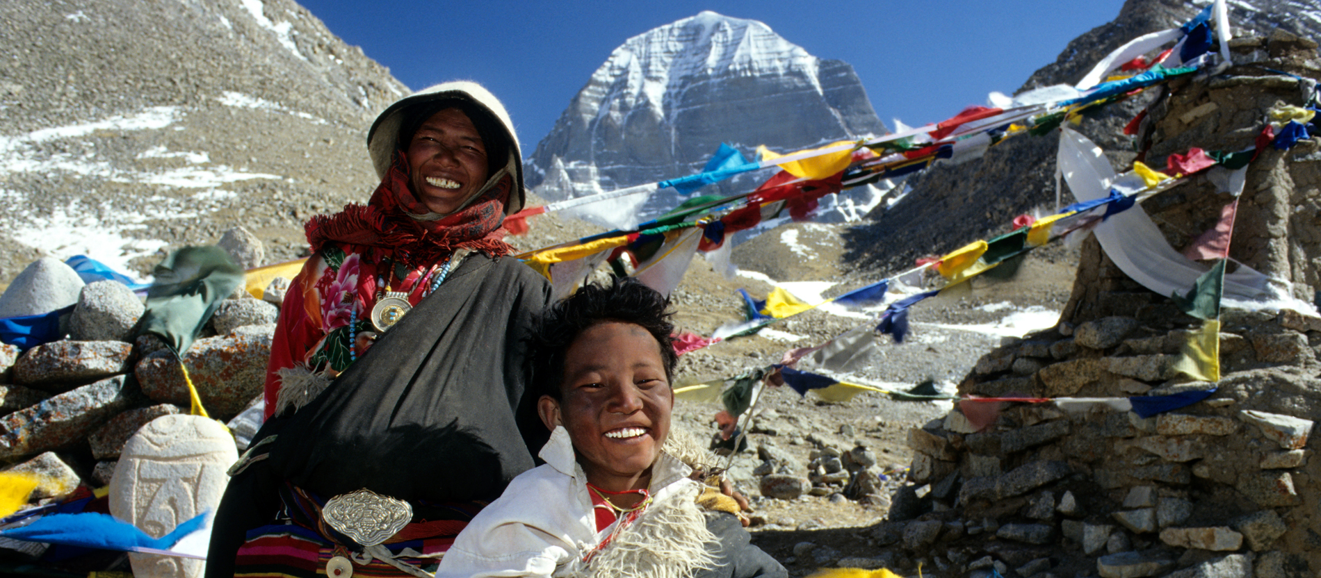 Pilger vor aufgespannten Gebetsfahnen am Berg Kailash in Tibet.
