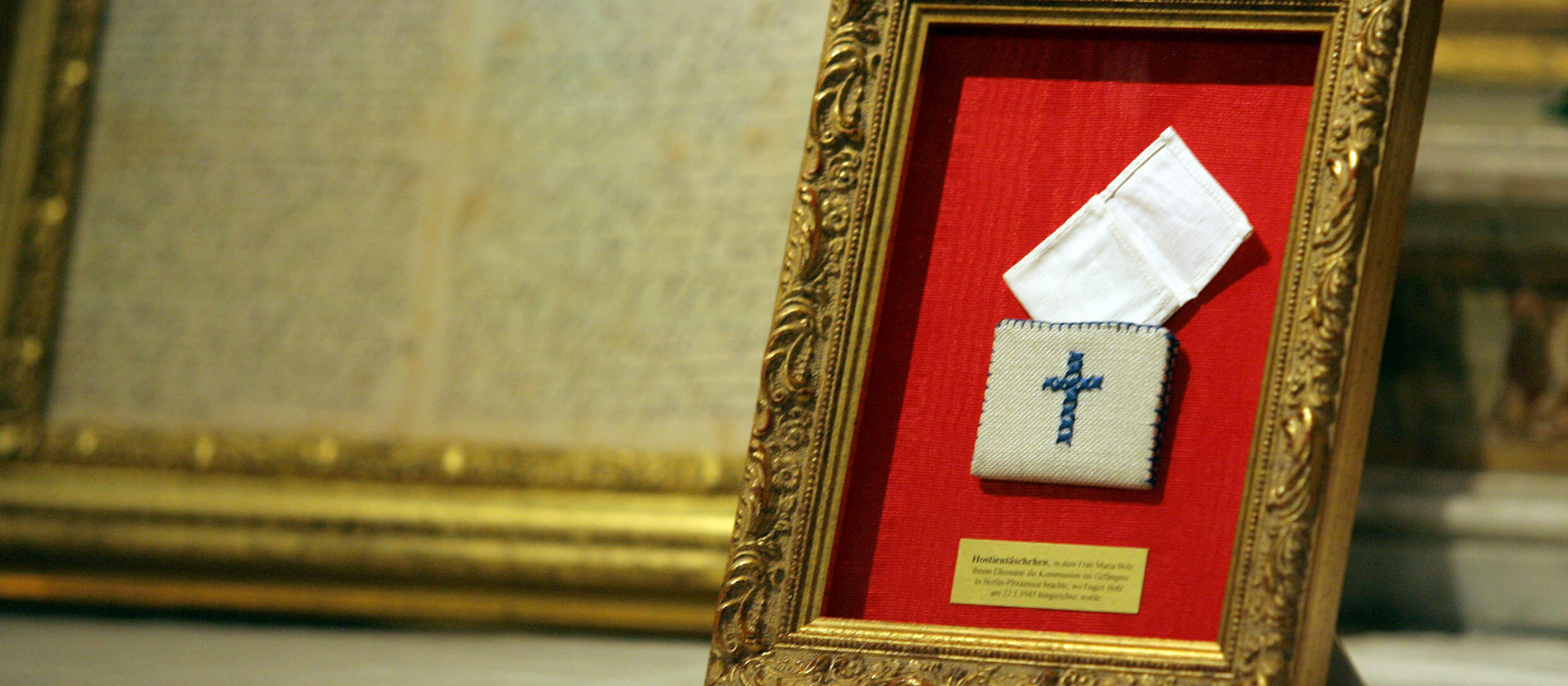 Ein Mäppchen mit einem Kreuz steht in einem Rahmen in der Kirche San Bartolomeo all’Isola