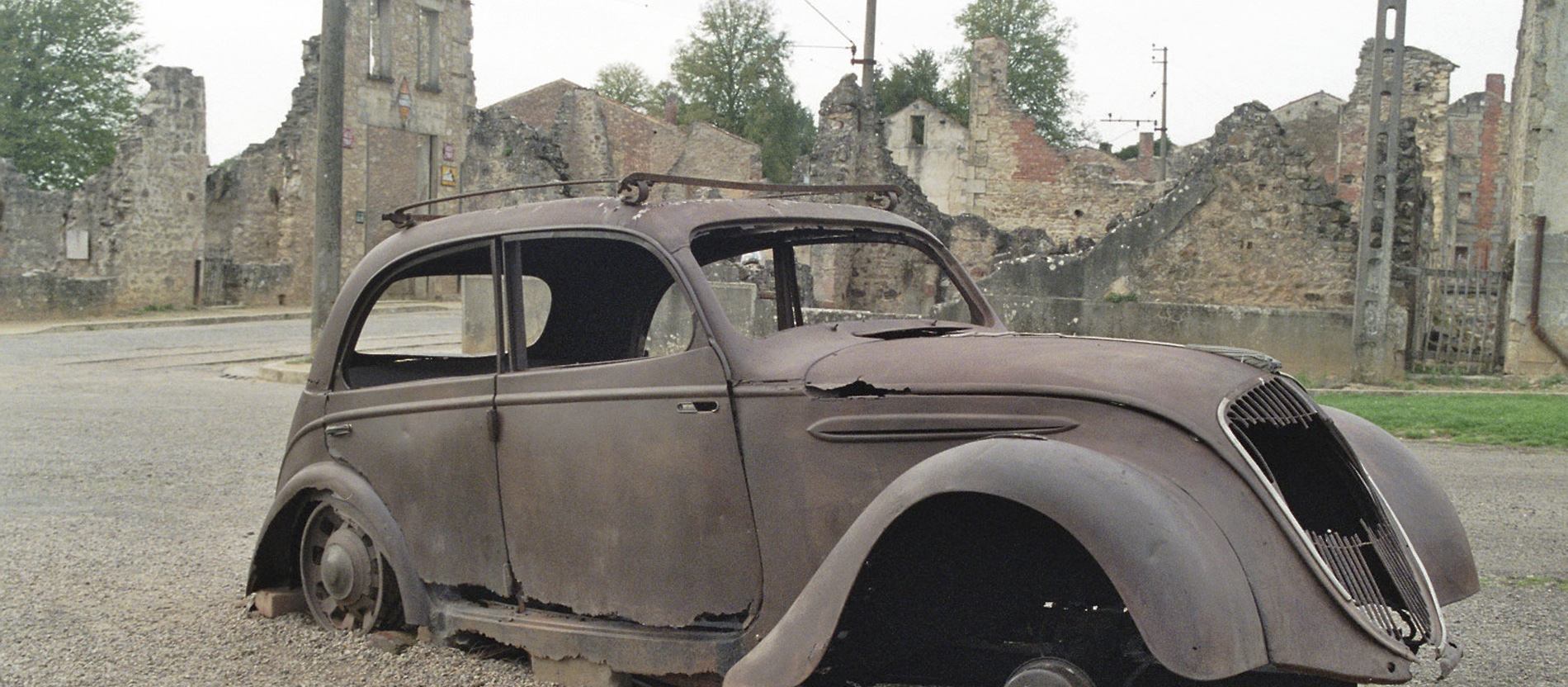 Das Wrack eines Autos aus den 1940er Jahren vor den Ruinen des französischen Dorfes Oradour-sur-Glane.