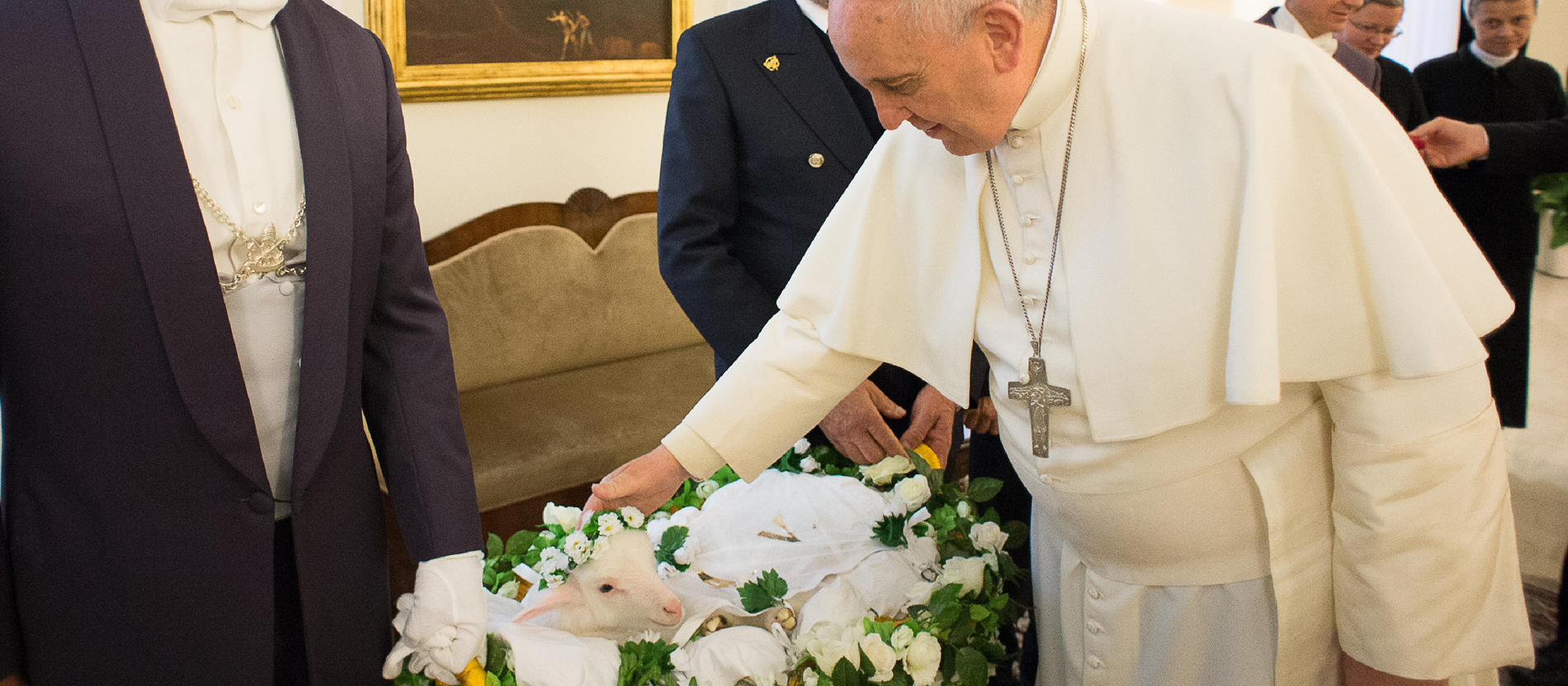 Papst Franziskus streichelt ein Lamm.