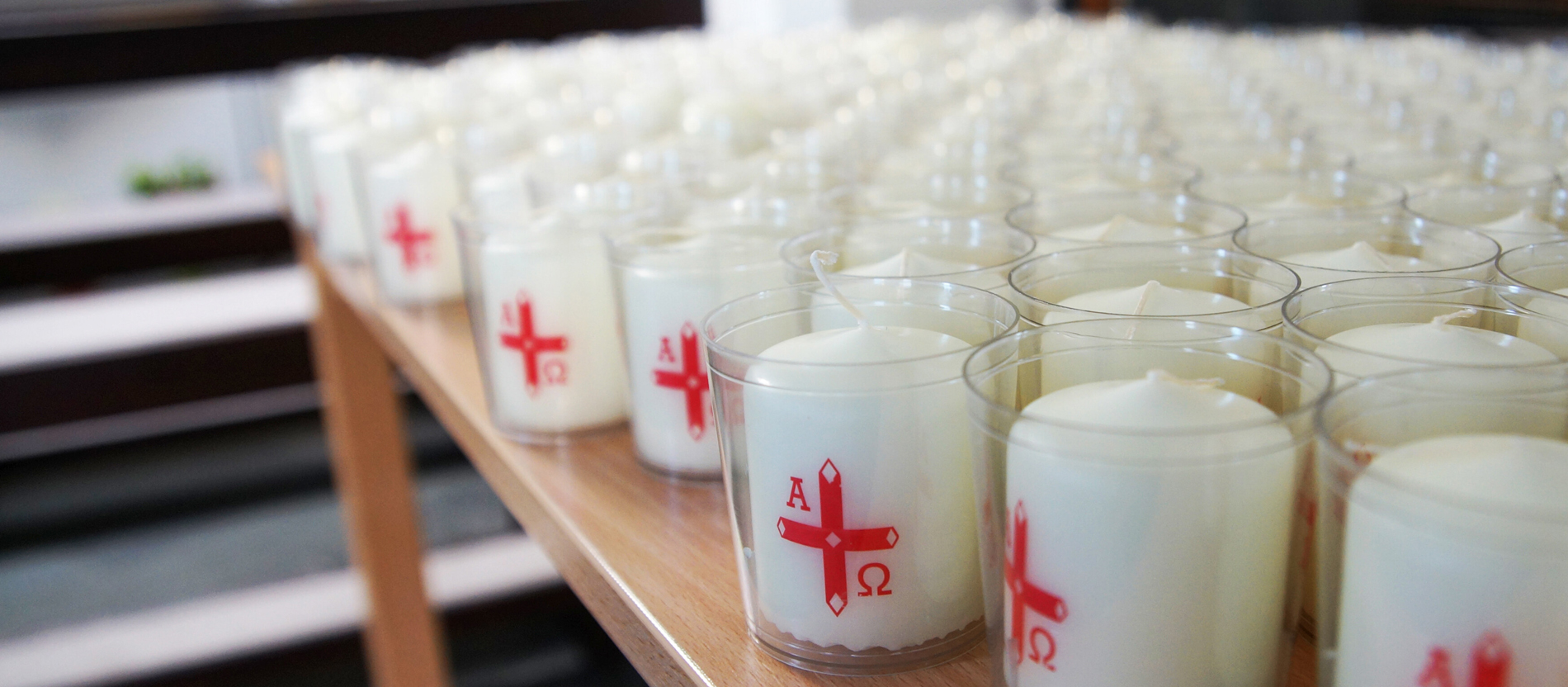 Viele kleine weiße Osterkerzen stehen auf einem Tisch in einer Kirche