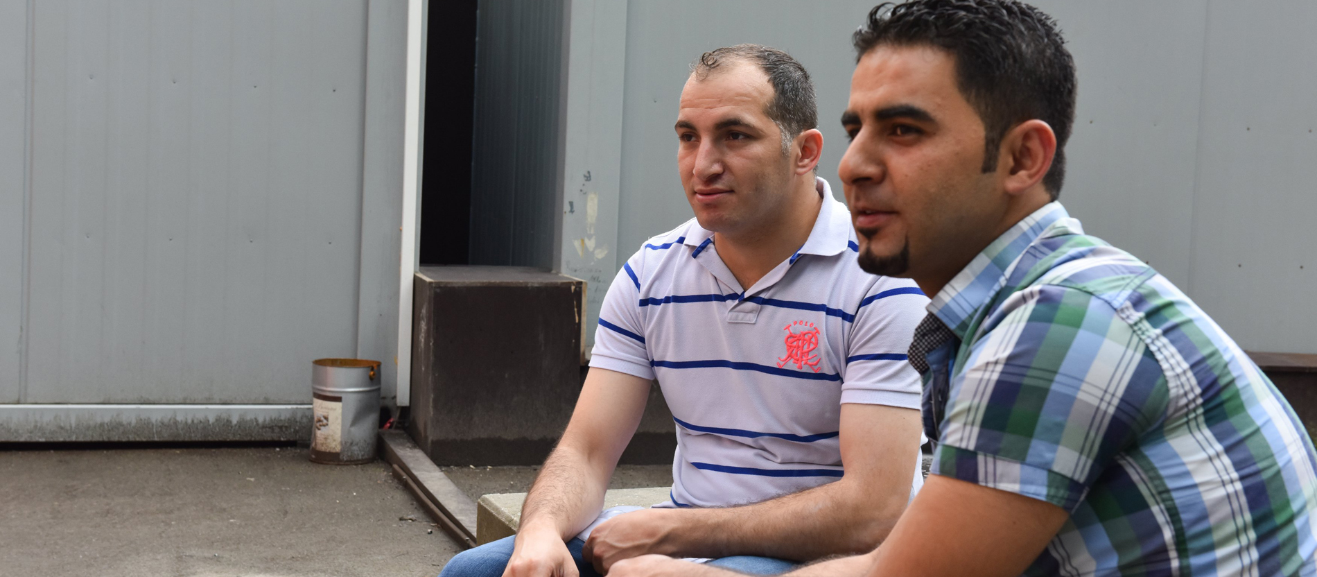 Zwei syrische Flüchtlinge sitzen vor einer Unterkunft der Caritas in Dortmund.