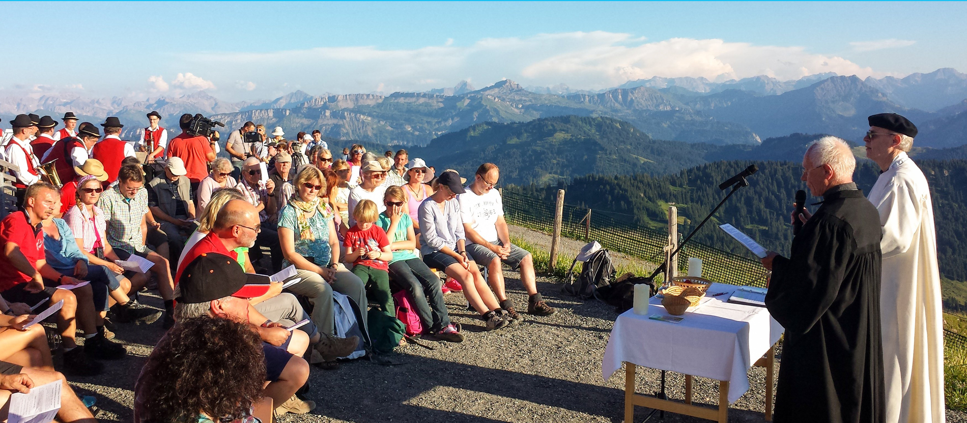 im Hintergrund Berge. Vorne ein ökumenischer Gottesdienst