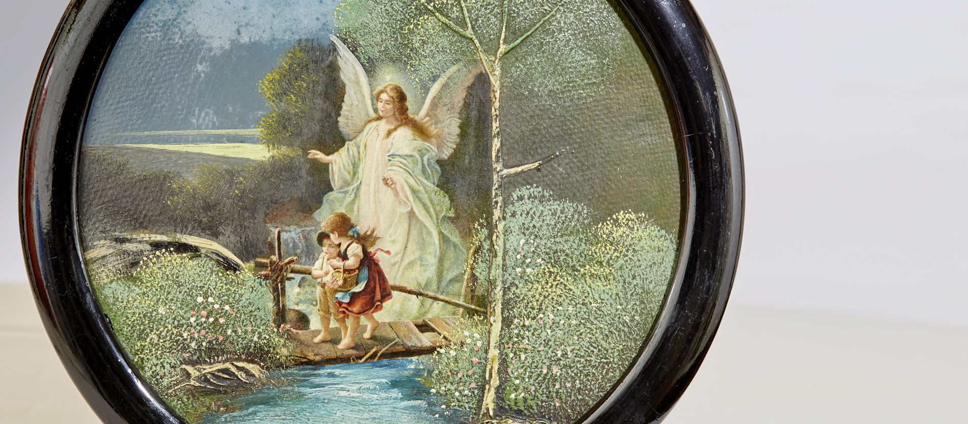 Auf einem runden Ölbild ist ein Schutzengel eingezeichnet, der hinter zwei kleinen Kindern steht und sie sicher über eine marode Brücke führt.