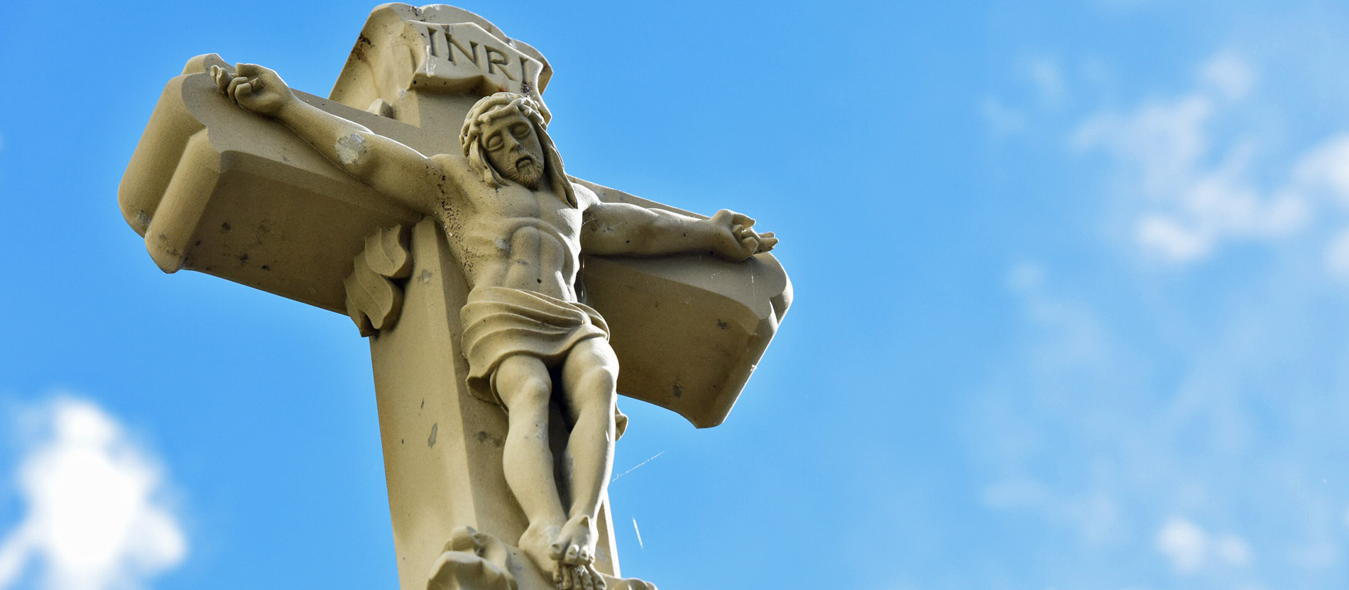 Ein Wegkreuz vor blauem Himmel.