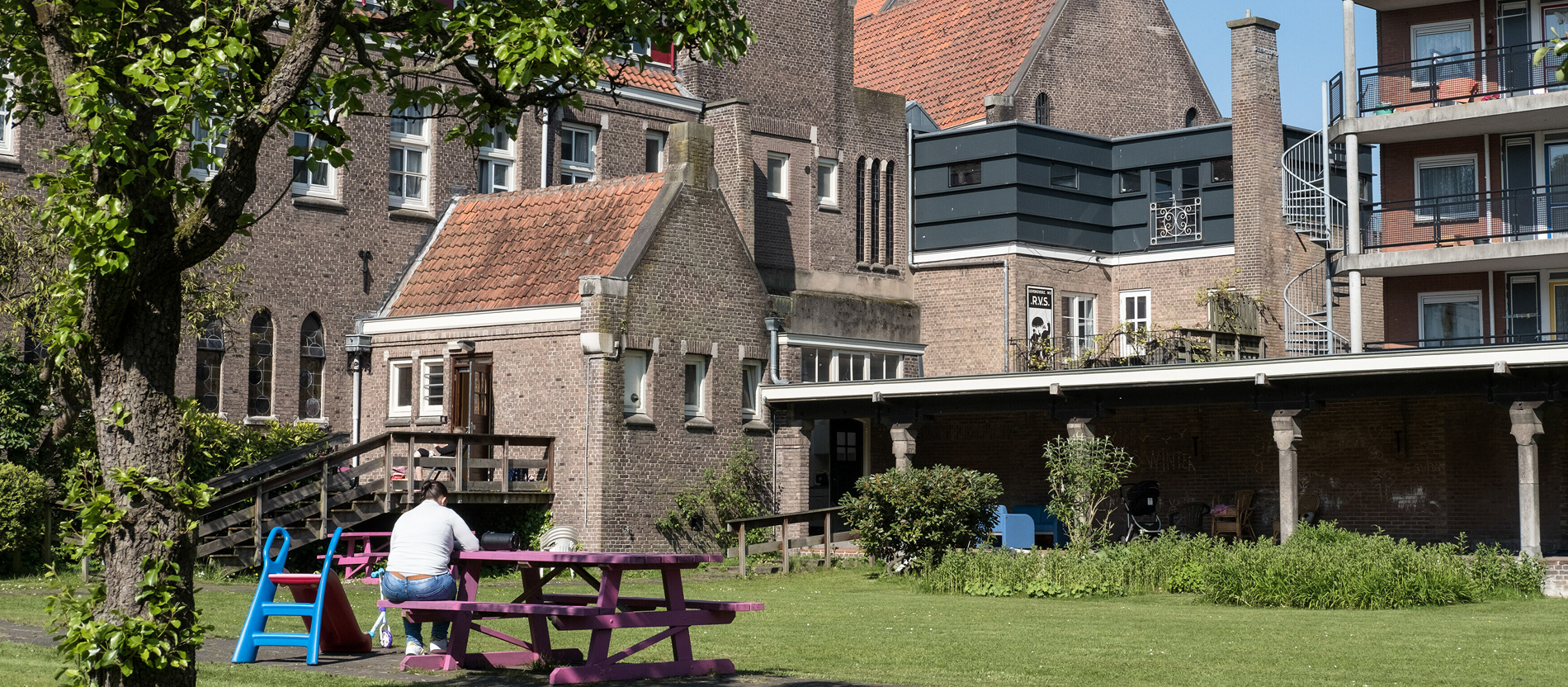 Eine Frau sitzt auf einer Bank im Garten eines ehemaligen Klosters in Amsterdam