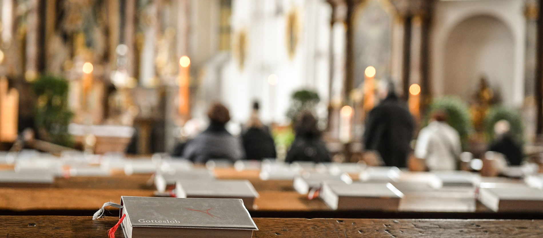 Gotteslob-Gesangbücher liegen auf Kirchenbänken.