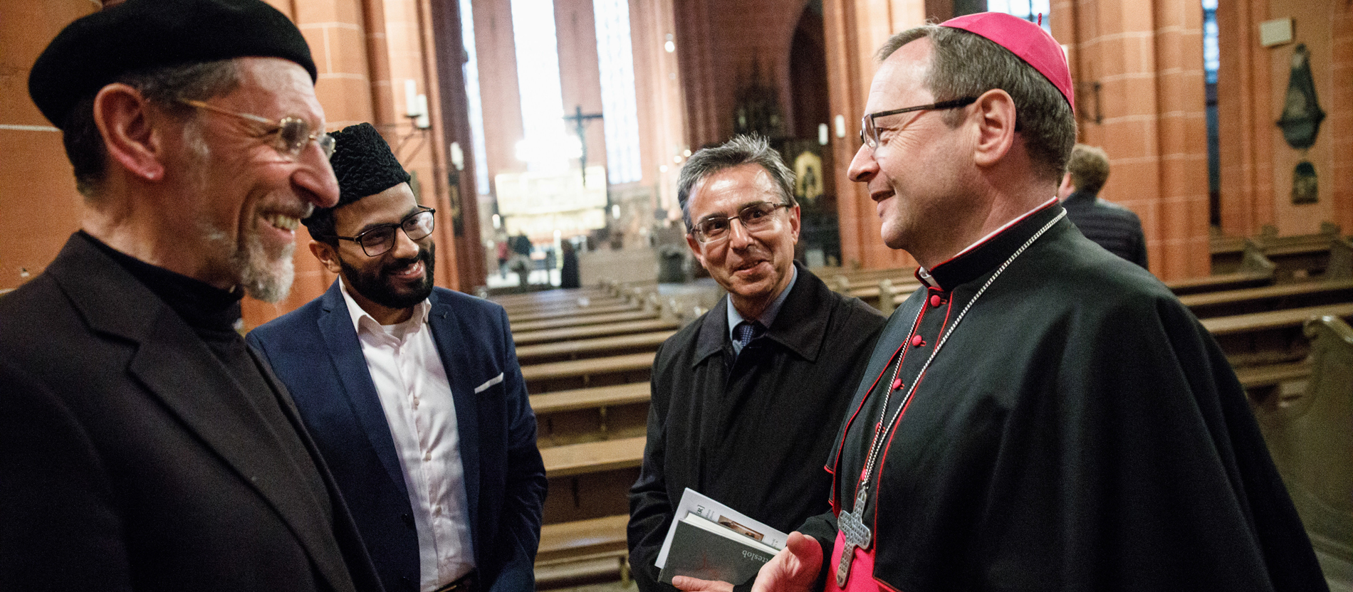Limburgs Bischof Georg Bätzing im Gespräch mit Teilnehmern eines interreligiösen Gebets.