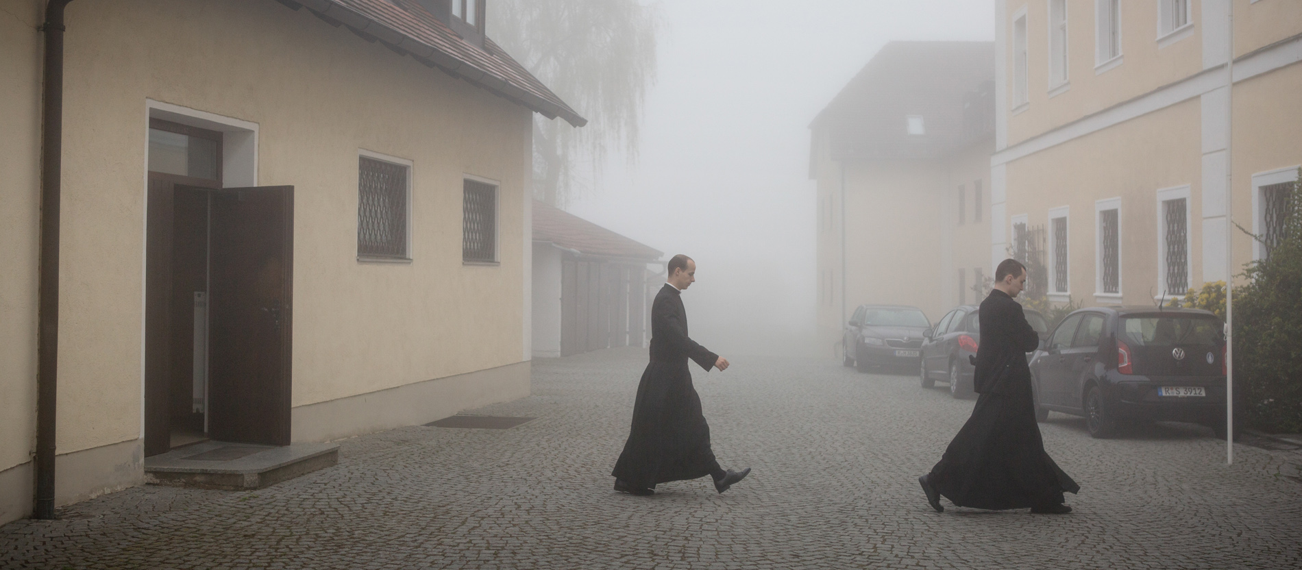 Seminaristen der Priesterbruderschaft St. Pius X.überqueren im Neben einen Platz