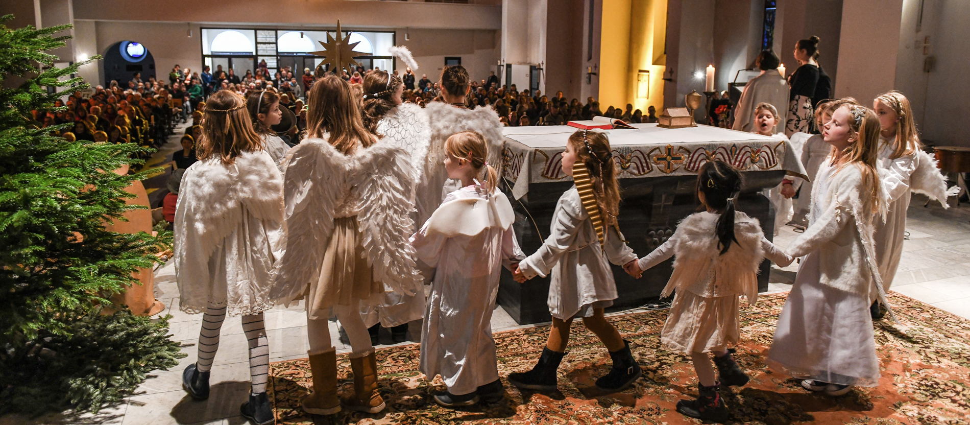 Kinder ziehen als Engel verkleidet um den Altar