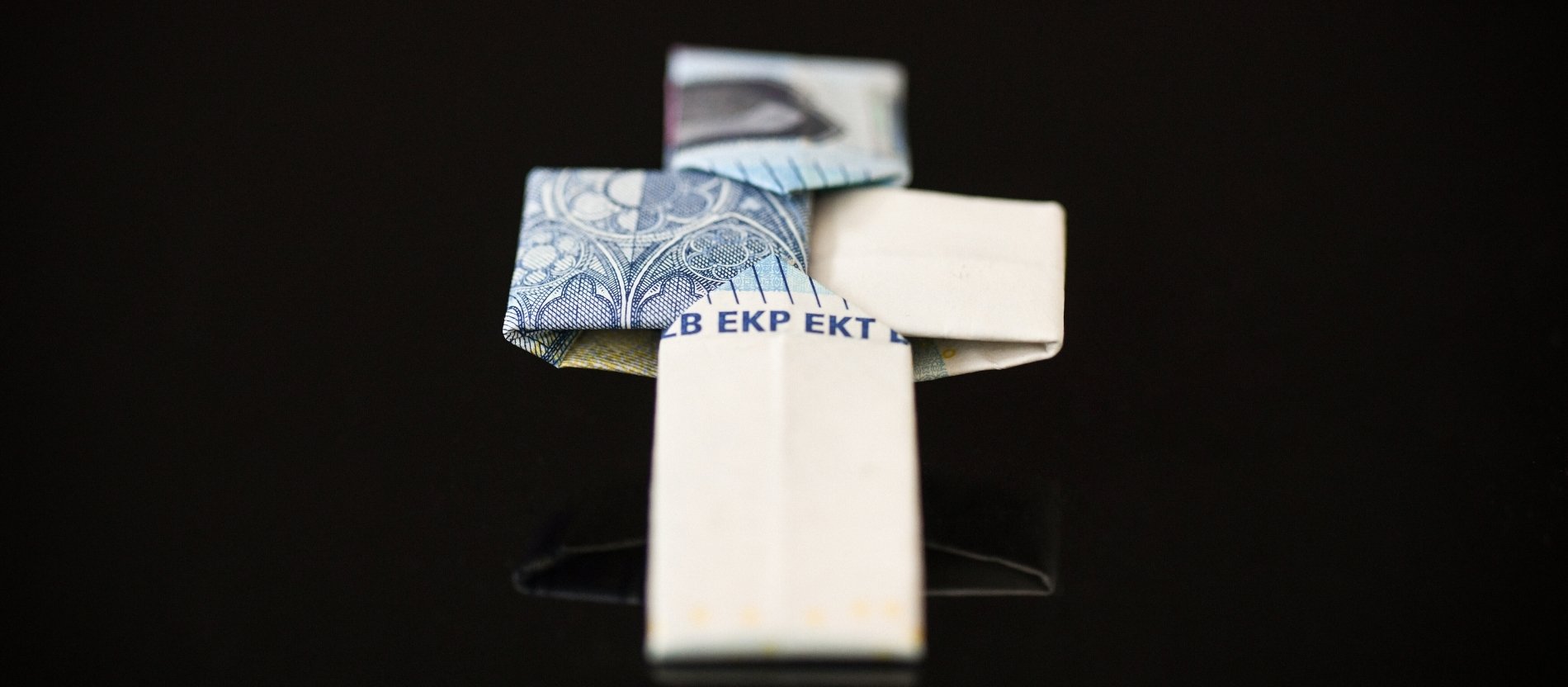 Ein aus einem Zwanzig-Euro-Geldschein gefaltetes Kreuz.