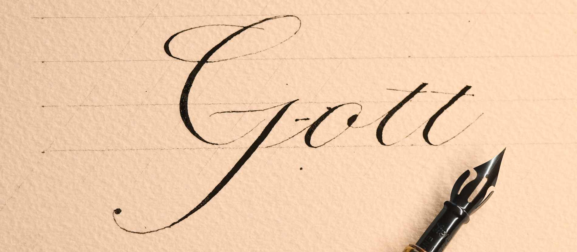 Auf einem Papier ist mit schwarzer Tusche das Wort Gott geschrieben