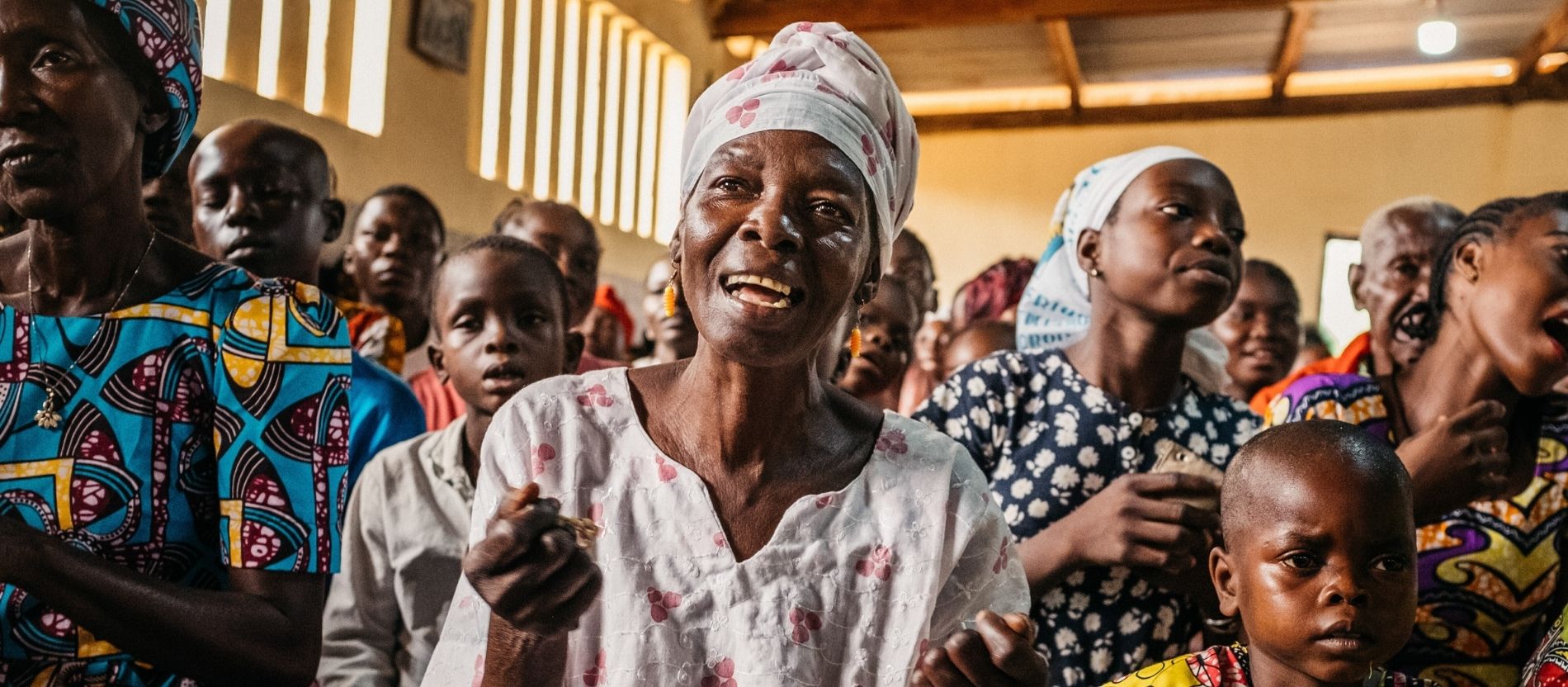 Frauen und Kinder in traditioneller Kleidung singen während der Sonntagsmesse in Afrika