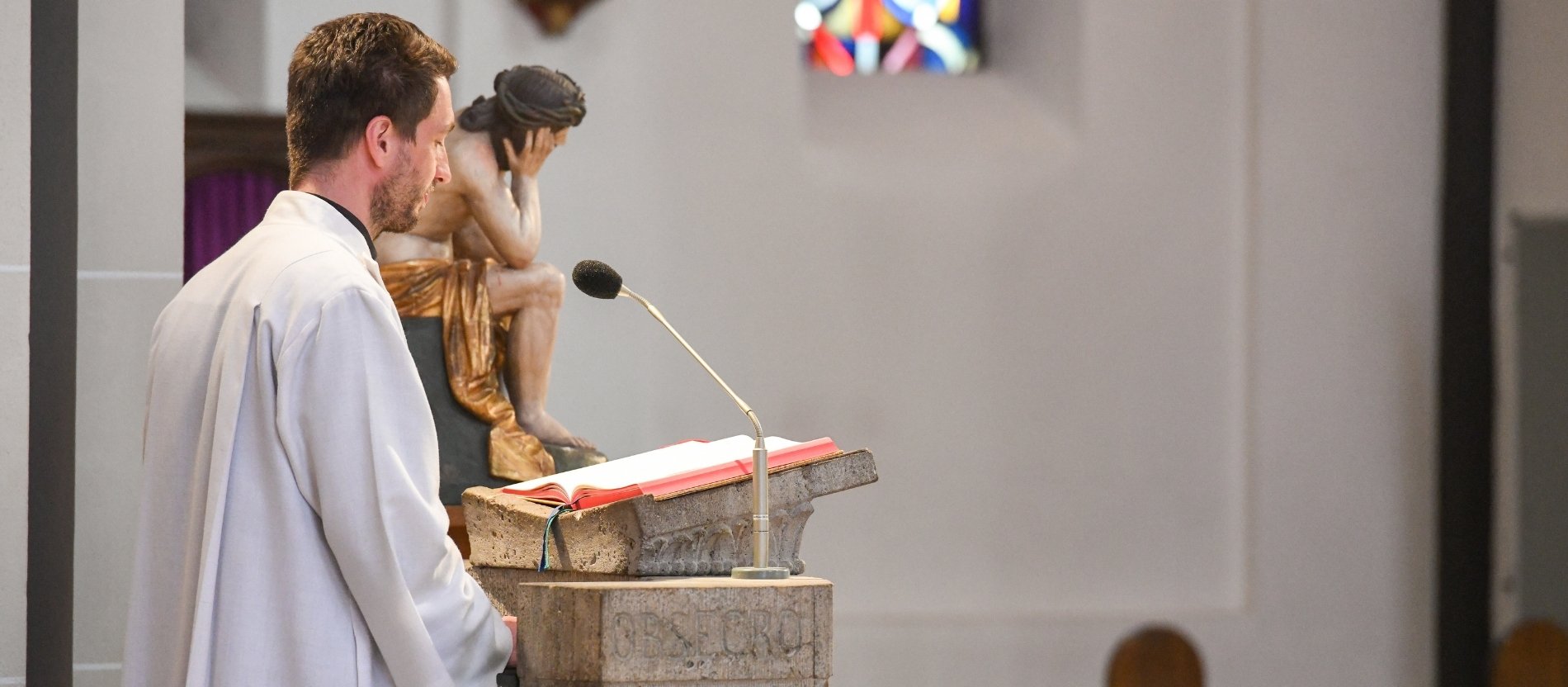 Lektor am Ambo bei einem Gottesdienst an Karfreitag in einer Kirche in Bonn.
