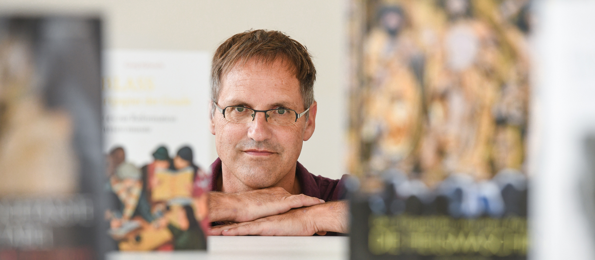 Georg Habenicht schaut zwischen einigen seiner Bücher in die Kamera