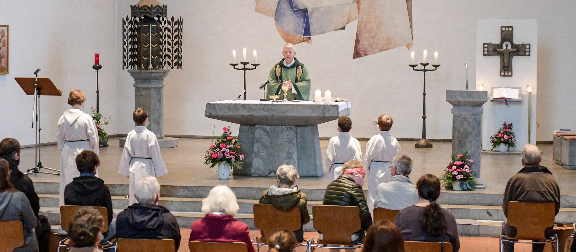 Ein Pfarrer hinter dem Altar davor die Gemeinde