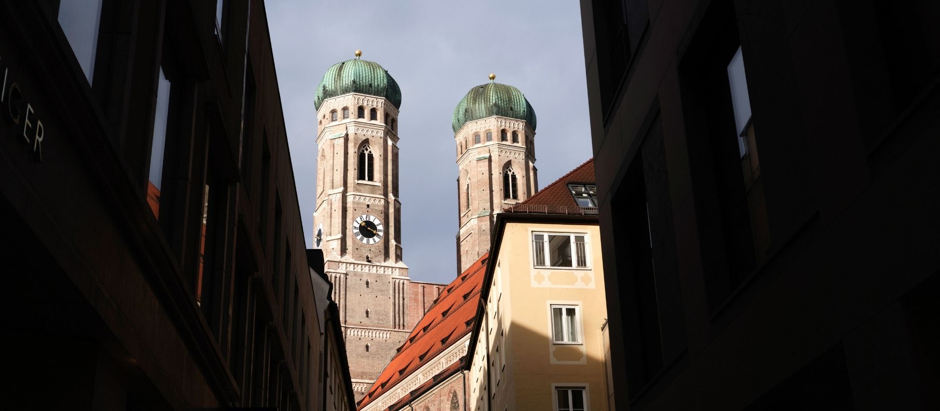 Blick auf die Kirchturmspitzen des Doms zu Unserer Lieben Frau durch eine Häuserreihe in München.