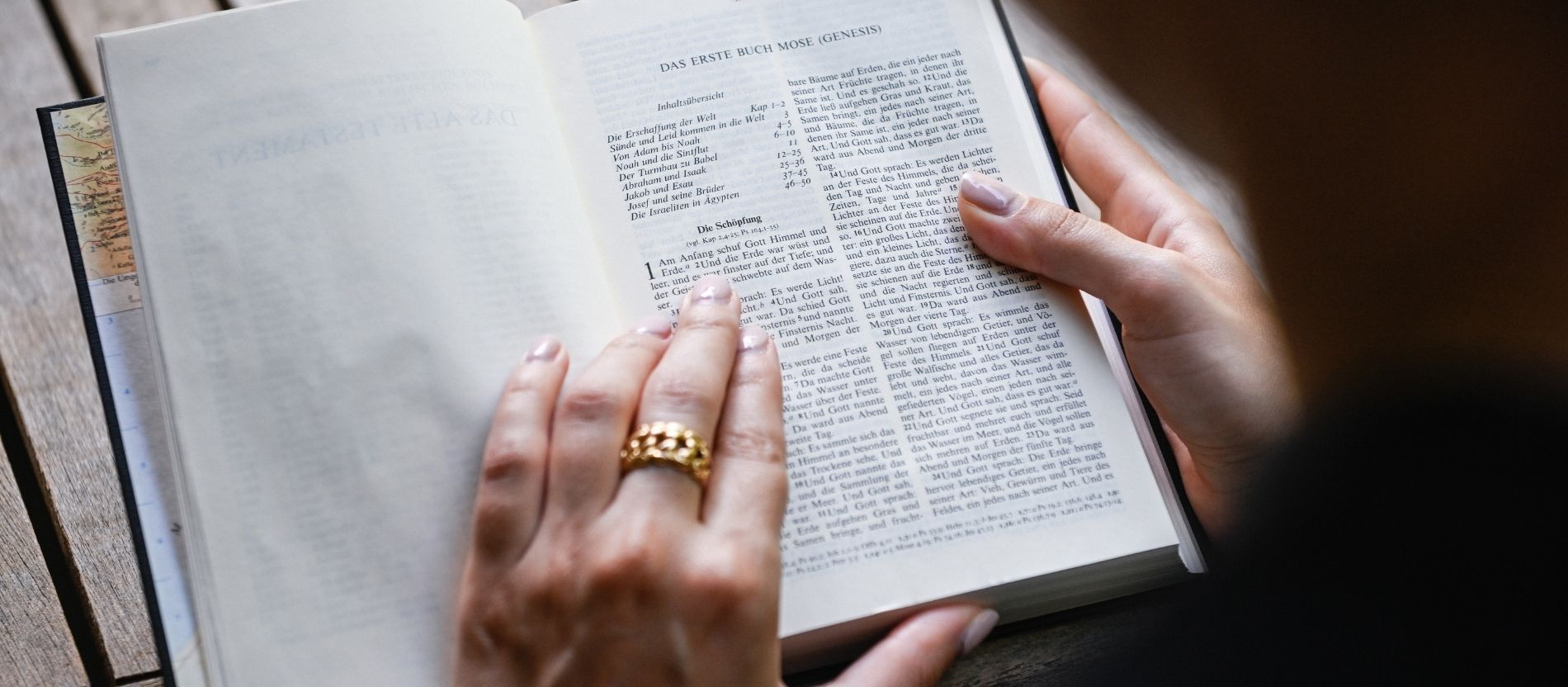 Eine junge Frau sitzt an einem Tisch und liest die Bibel