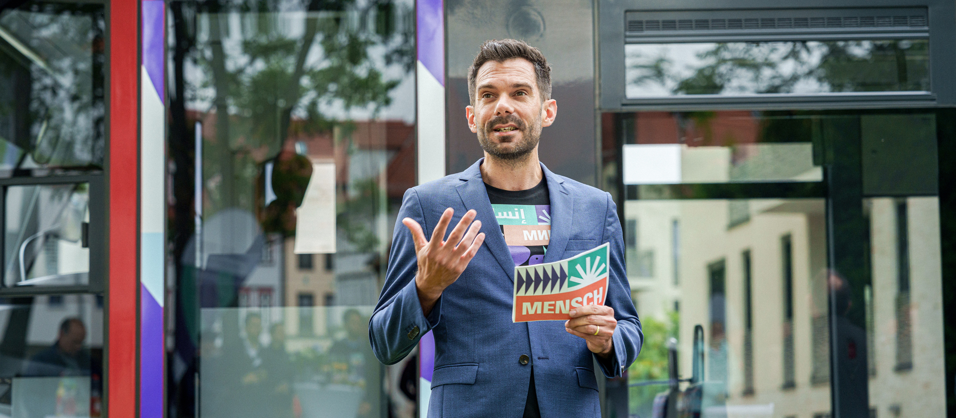 ZdK-Generalsekretär Marc Frings steht vor einer Straßenbahn und stellt das Katholikentagsmotto vor