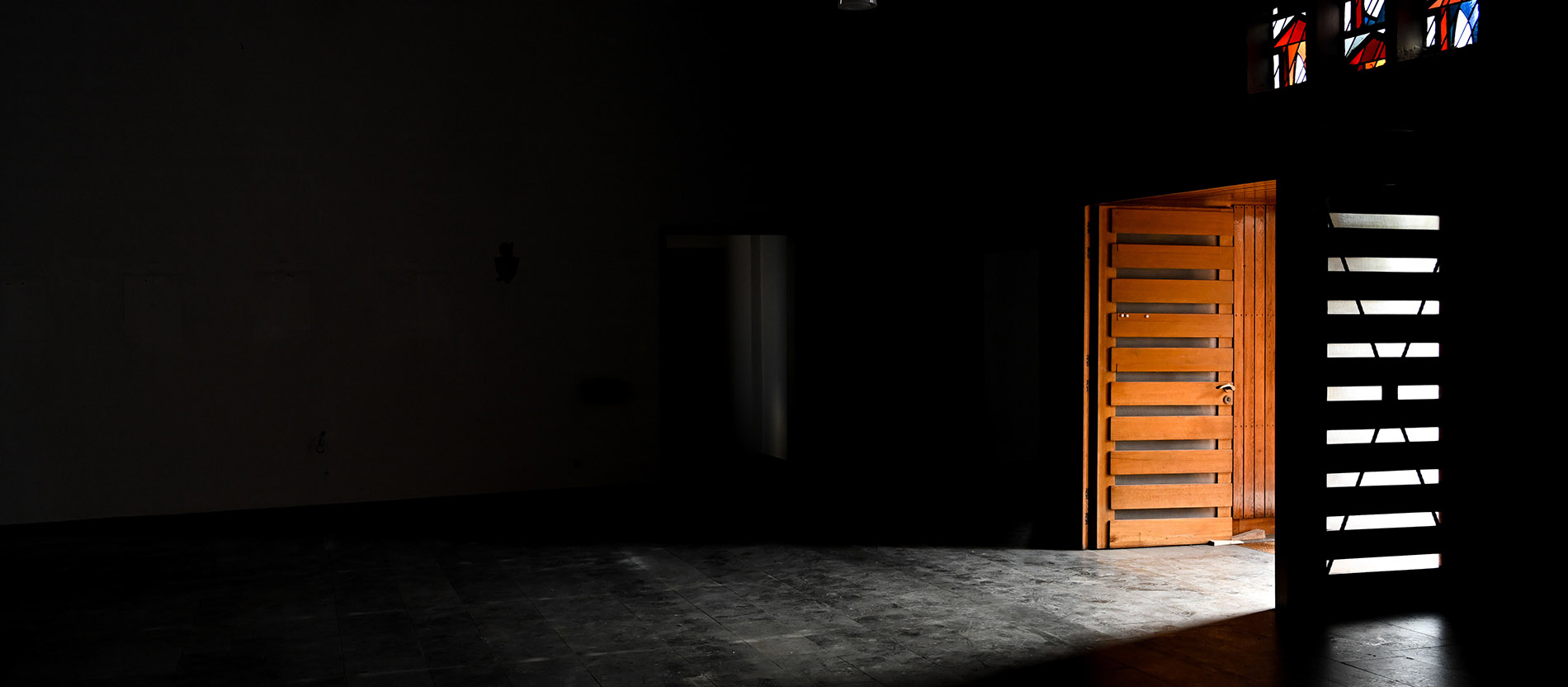 Eine Tür steht offen in der dunklen, profanierten und leer geräumten Kirche Zur Heiligen Familie in Rhede.