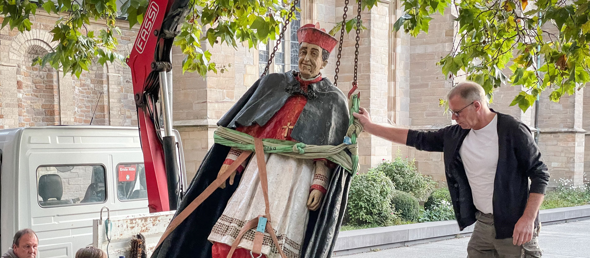 Die Statue von Kardinal Franz Hengsbach vor dem Essener Dom wird mit einem Kran auf einen Transporter gehoben.