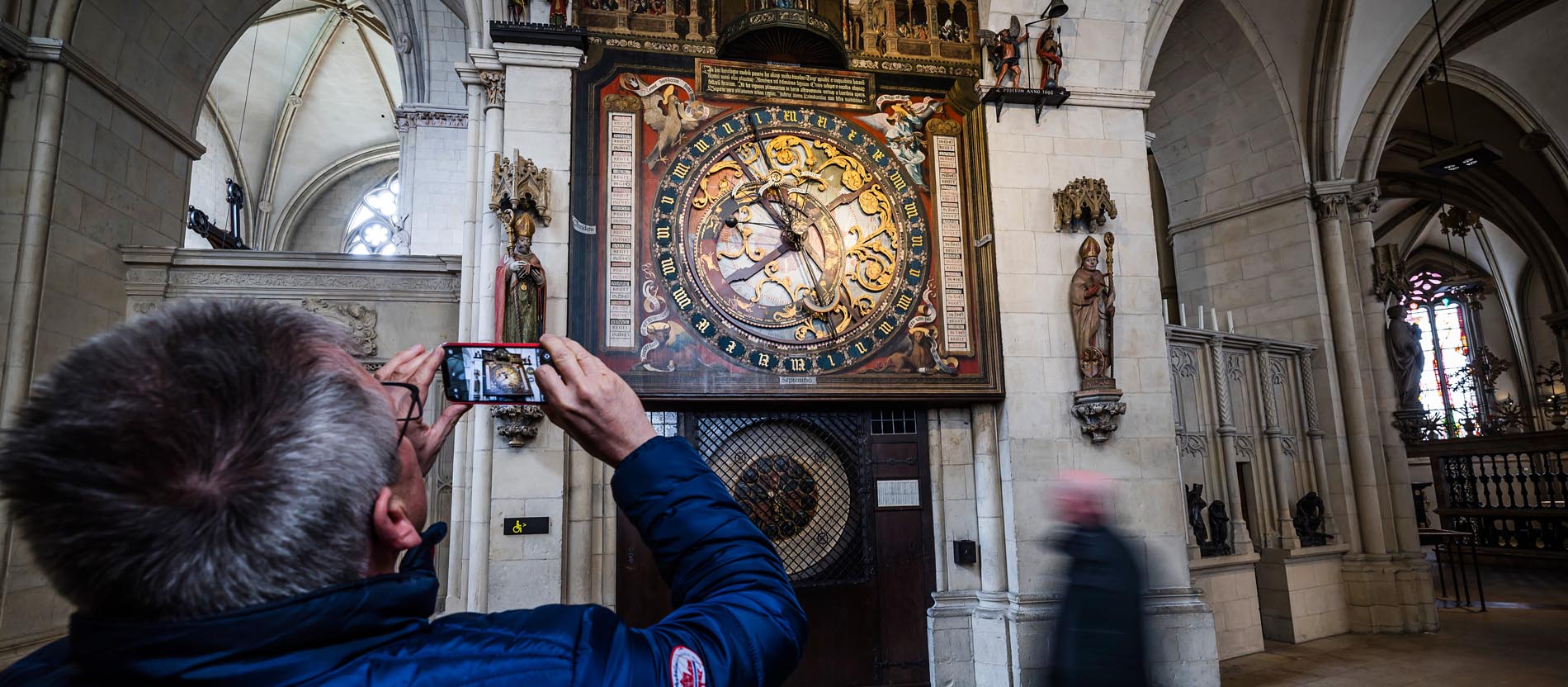 Ein Besucher macht ein Foto von der Astronomischen Uhr im Chorumgang des Sankt-Paulus-Doms in Münster.