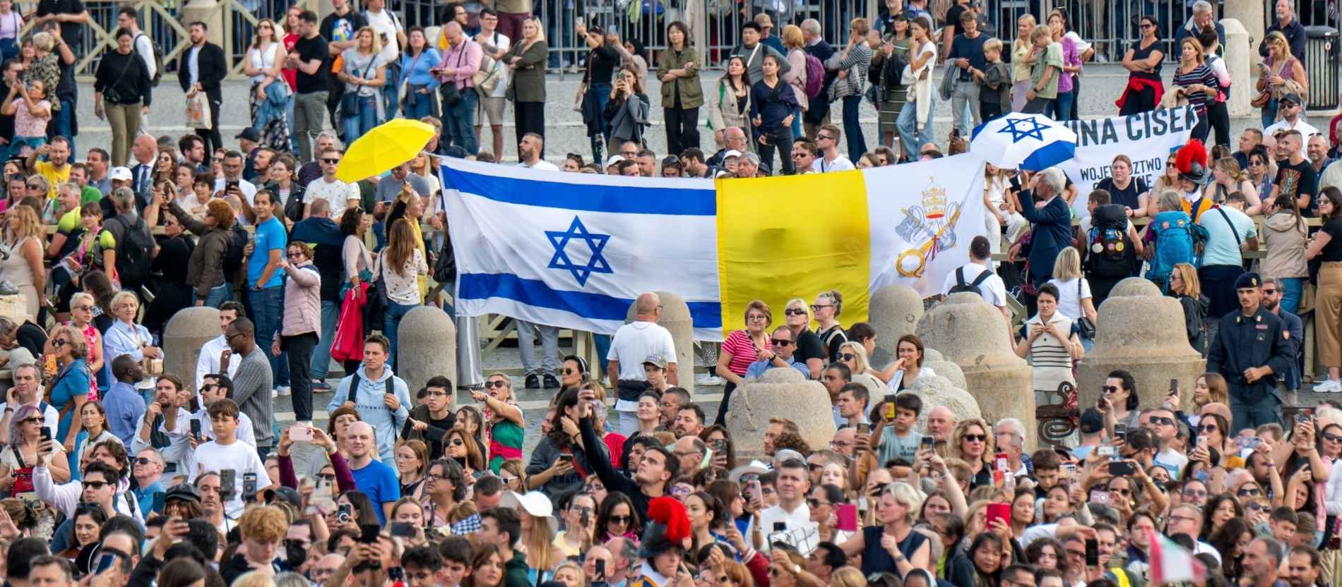 Menschen auf dem Petersplatz halten die Fahnen von Israel und dem Vatikan nebeneinander